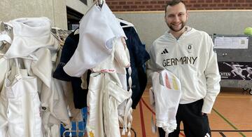 Rack of clothes with young man in sports clothing right next it.