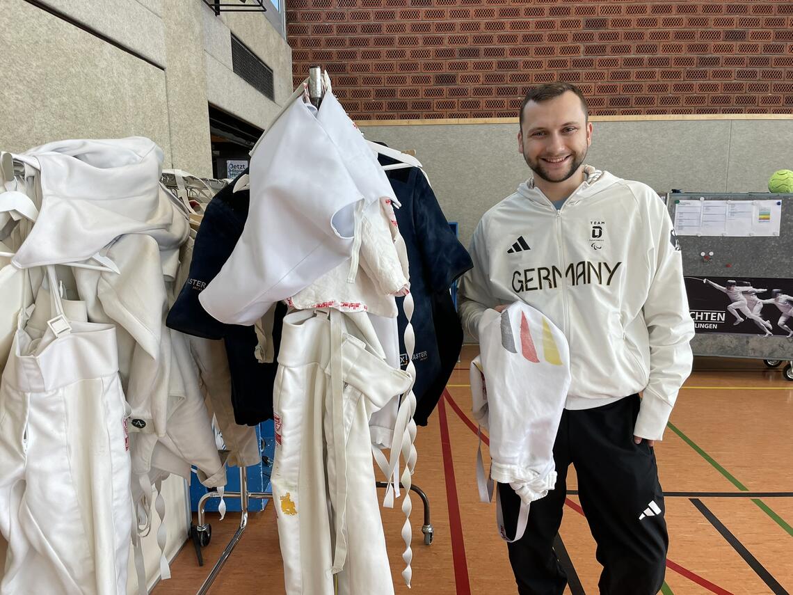 Rack of clothes with young man in sports clothing right next it.