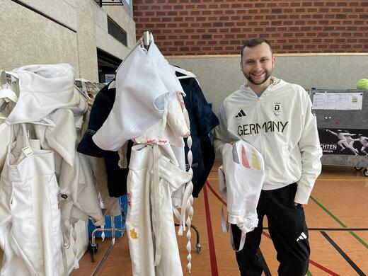 Rack of clothes with young man in sports clothing right next it.